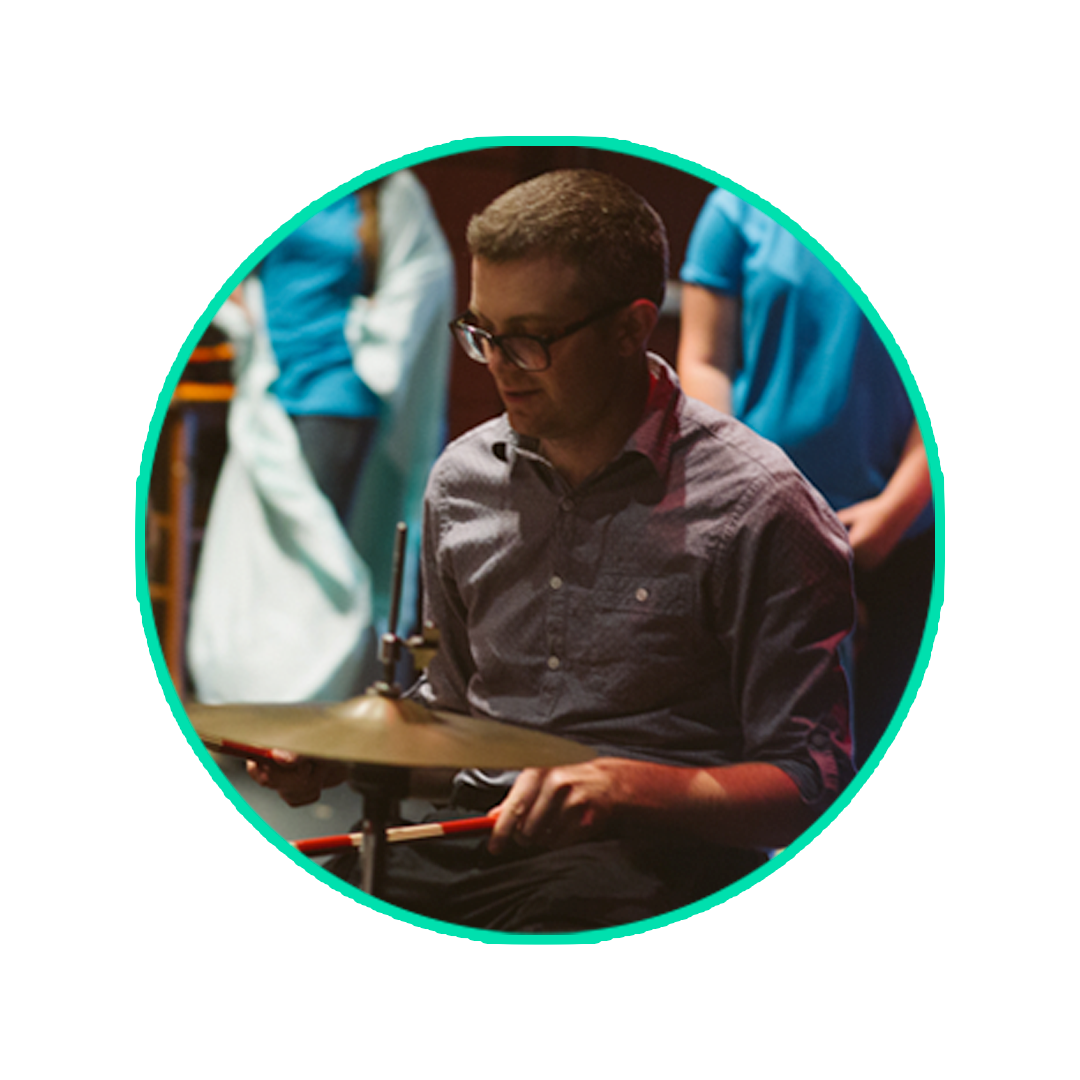 Music educator seated at a percussion setup during a rehearsal or performance
